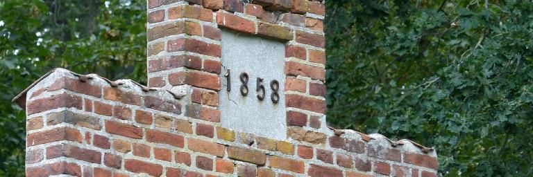Close up of the fish house brick gable with the inscription 1858